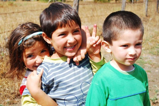 Tres niños sonriendo en el campo