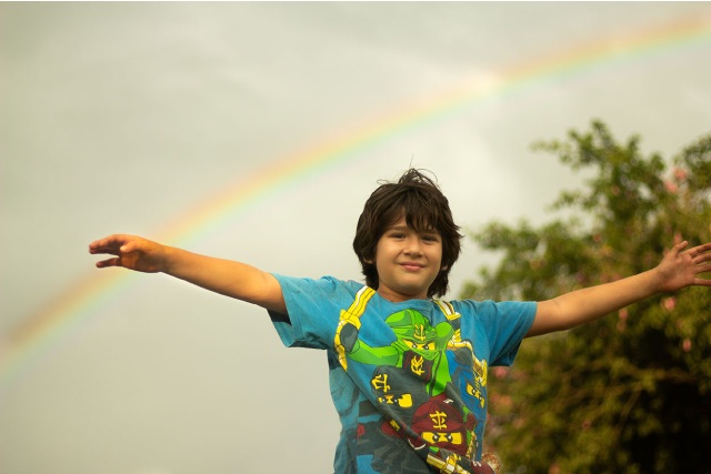 Niño con un arcoíris de fondo